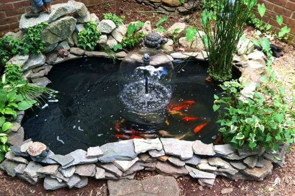kolam ikan mini di teras rumah dengan batu alam